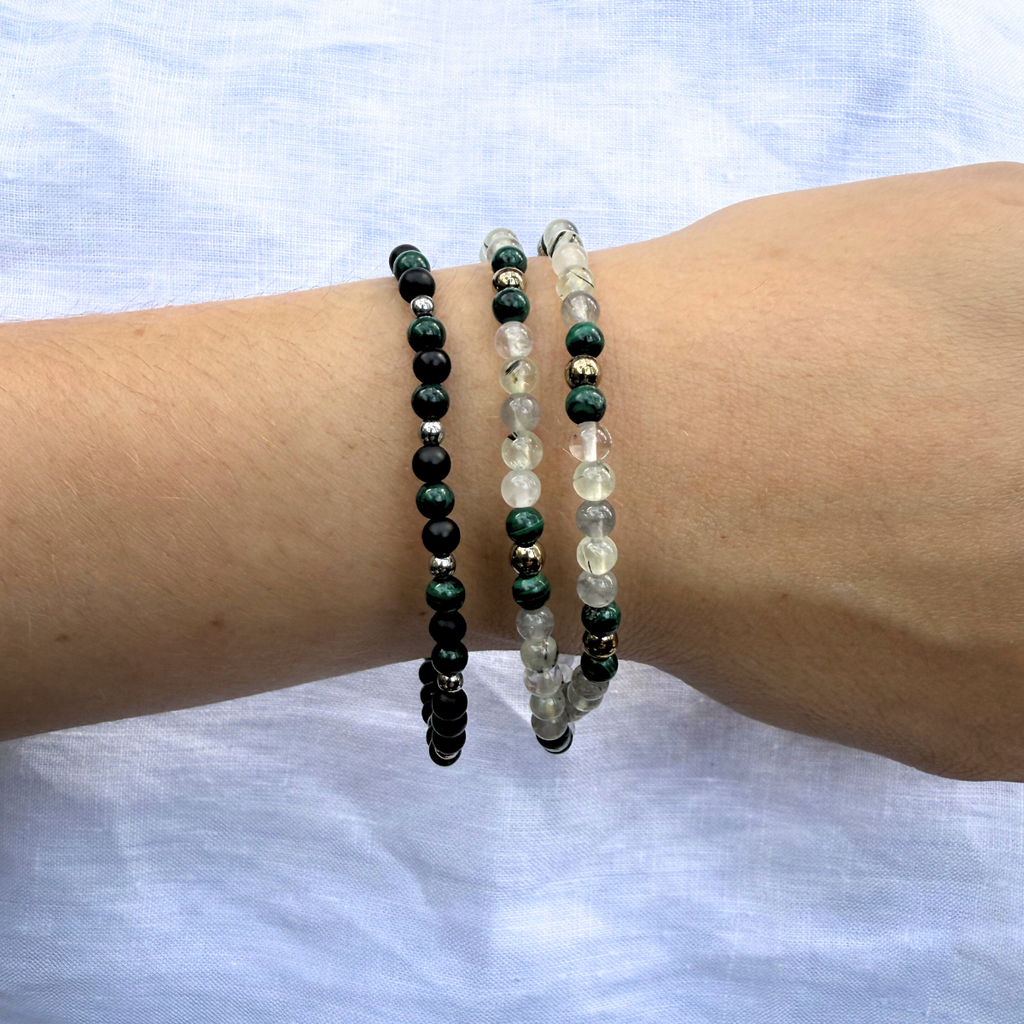 Two crystals bracelets on a wrist against a light fabric background